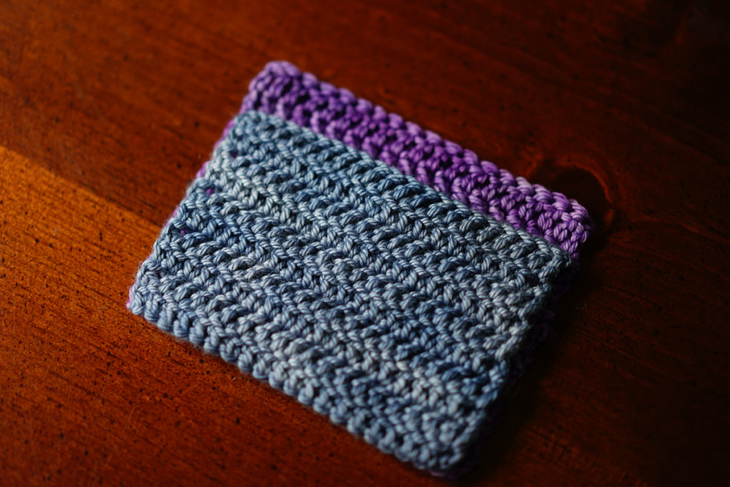 A grey crochet swatch showing the difference in yarn over directions