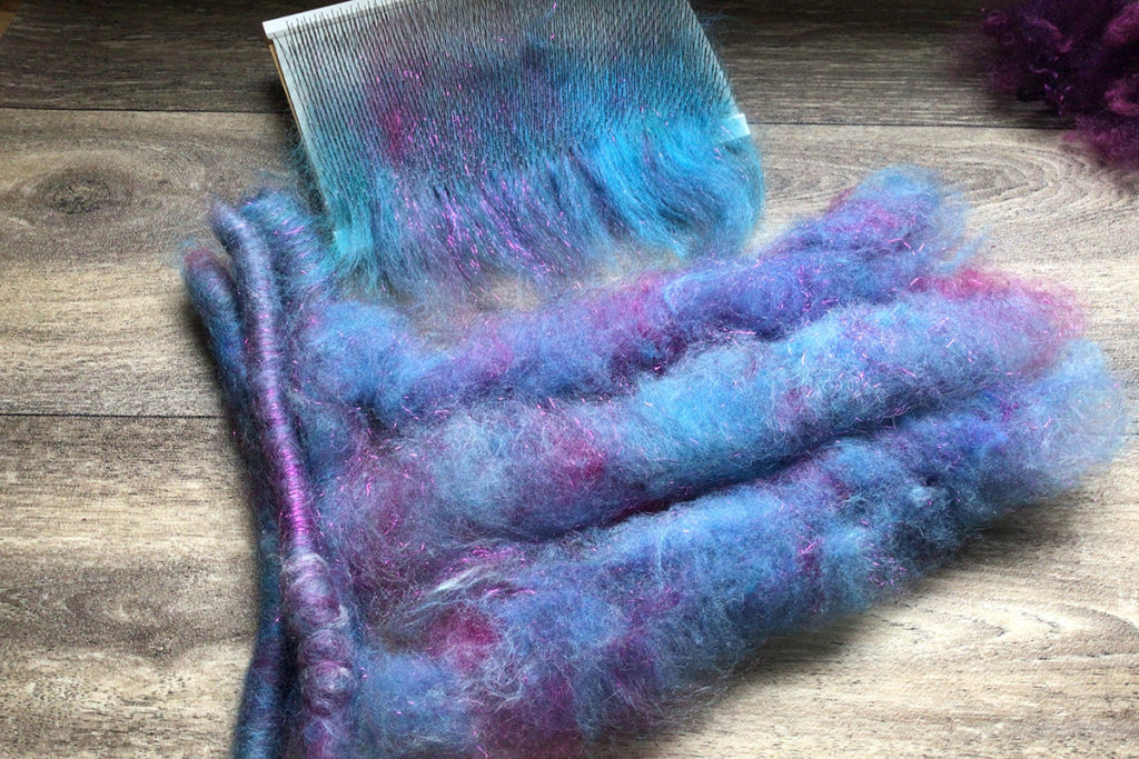 purple and blue fiber on a carder in article: Fibre Processing at Home: Which Blending Tool(s) Should I Buy First? Debbie Held