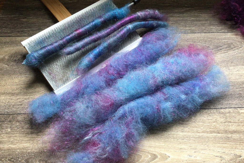 purple and blue fiber on a carder in article: Fibre Processing at Home: Which Blending Tool(s) Should I Buy First? Debbie Held
