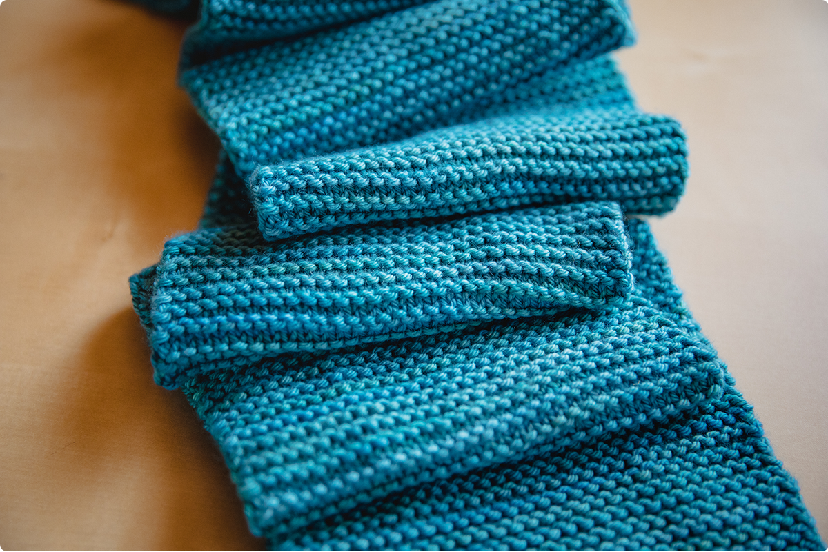 Pictured is a blue garter stitch beginner scarf.